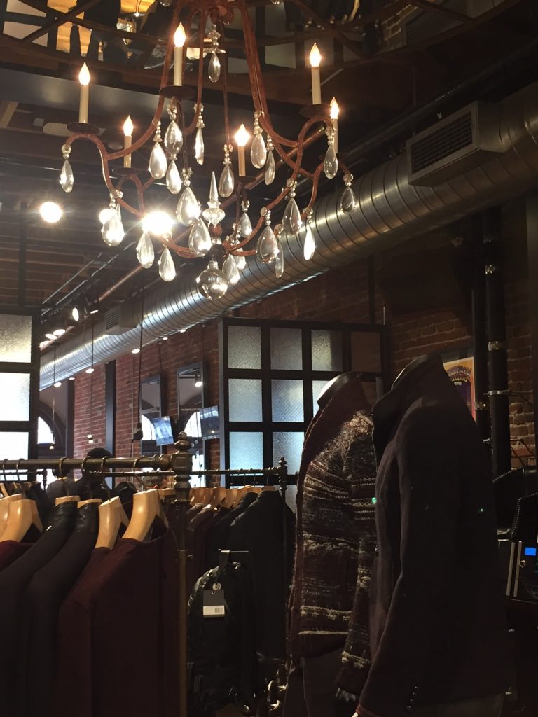 An elegant chandelier and industrial decor make for a chic and edgy San Francisco showroom and retail space. Image Source: Fashion School Daily
